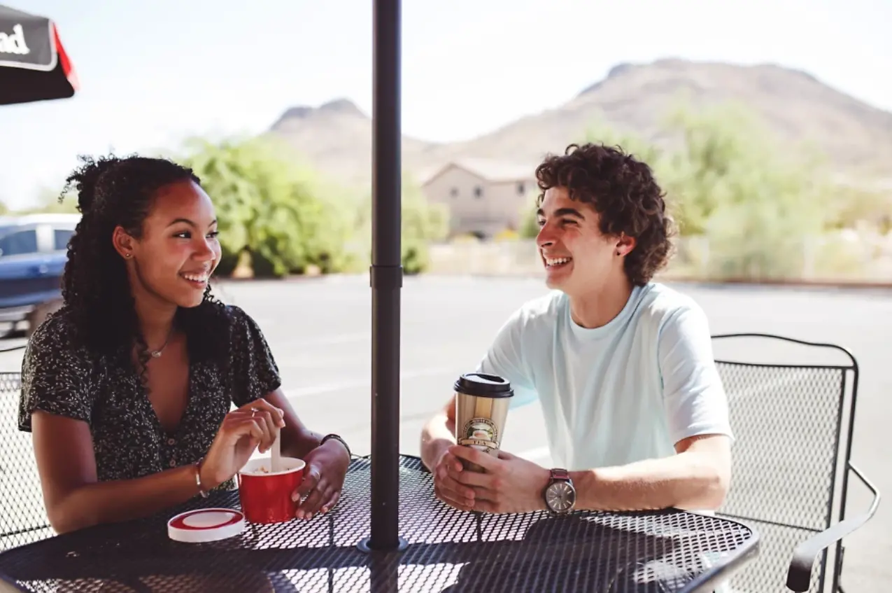 Two people smiling and holding paper cups.