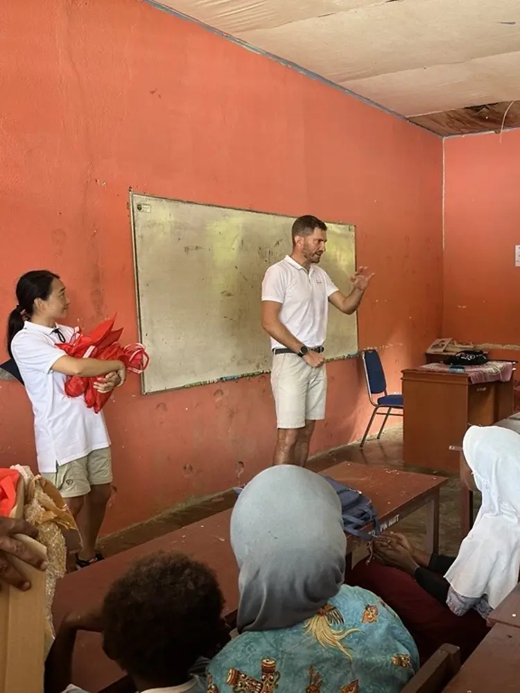 Seseorang berdiri di depan sekelompok orang di ruang kelas.