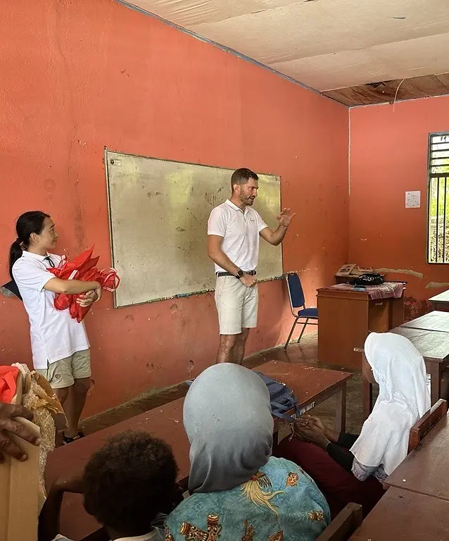 Seseorang berdiri di depan sekelompok orang di ruang kelas.