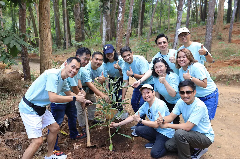 A group of people in blue t-shirts planting a tree.