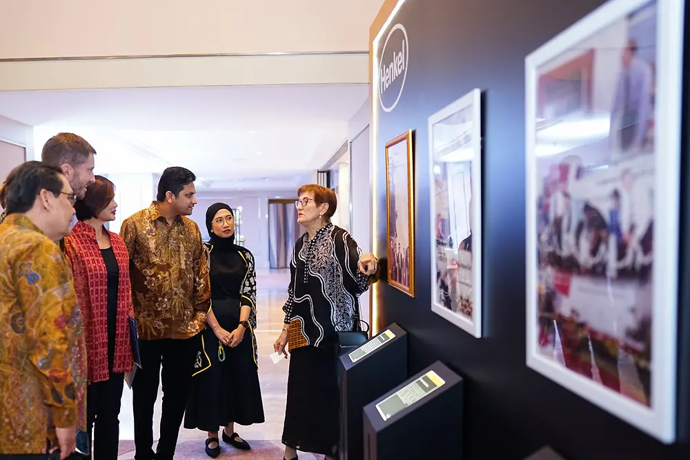 A group of people looking at a picture on a wall.