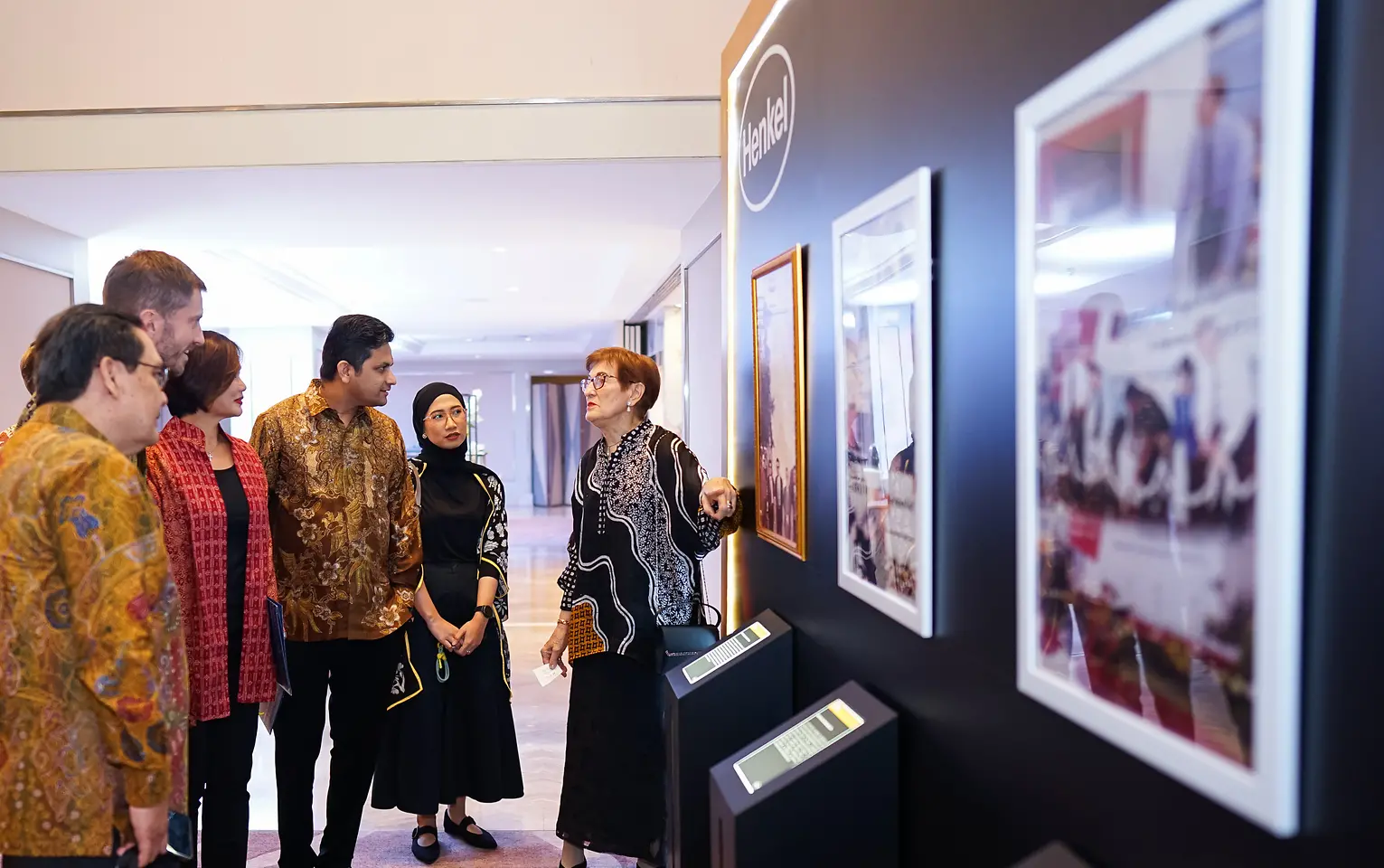 A group of people looking at a picture on a wall.