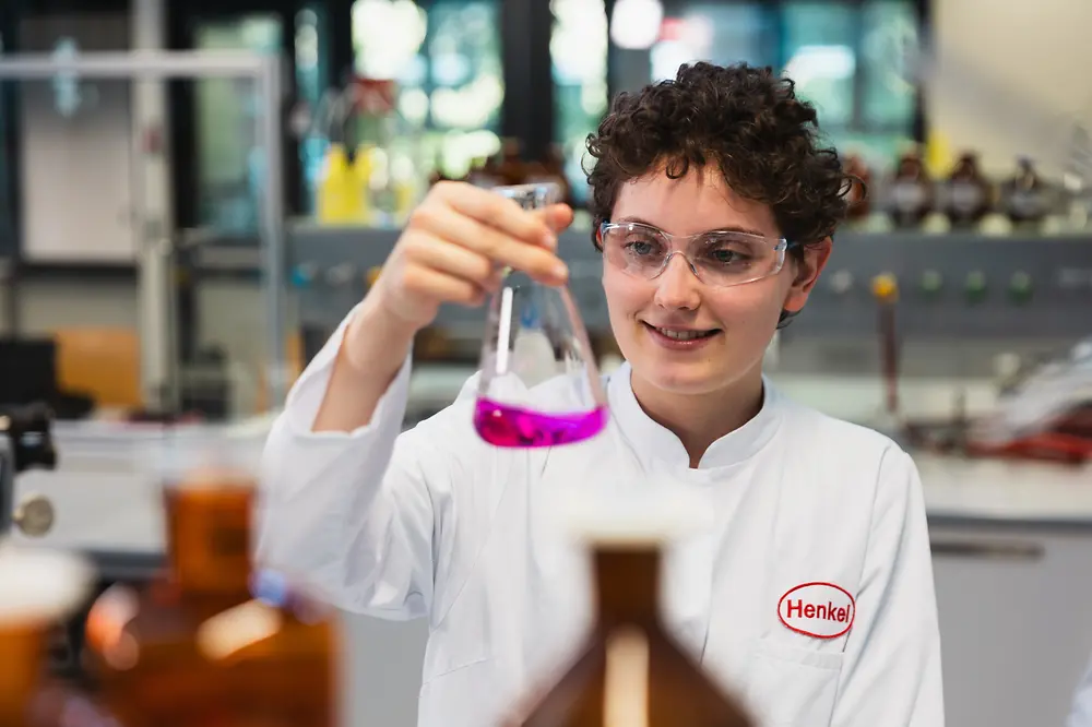 A person holding a flask with purple liquid.